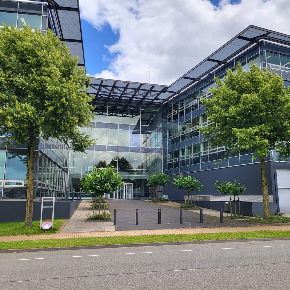 Modern kantoorgebouw met glazen gevel en bomen ervoor