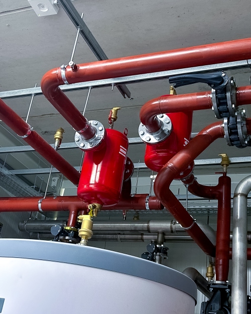 Rode verwarmingsleidingen met appendages in een technische ruimte